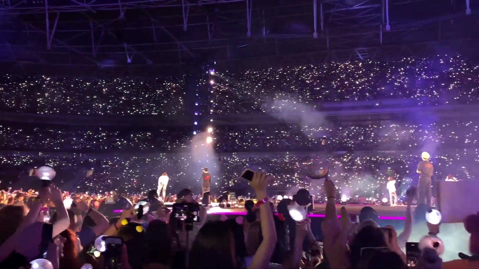 BTS performing in concert at a packed stadium before a crowd of fans