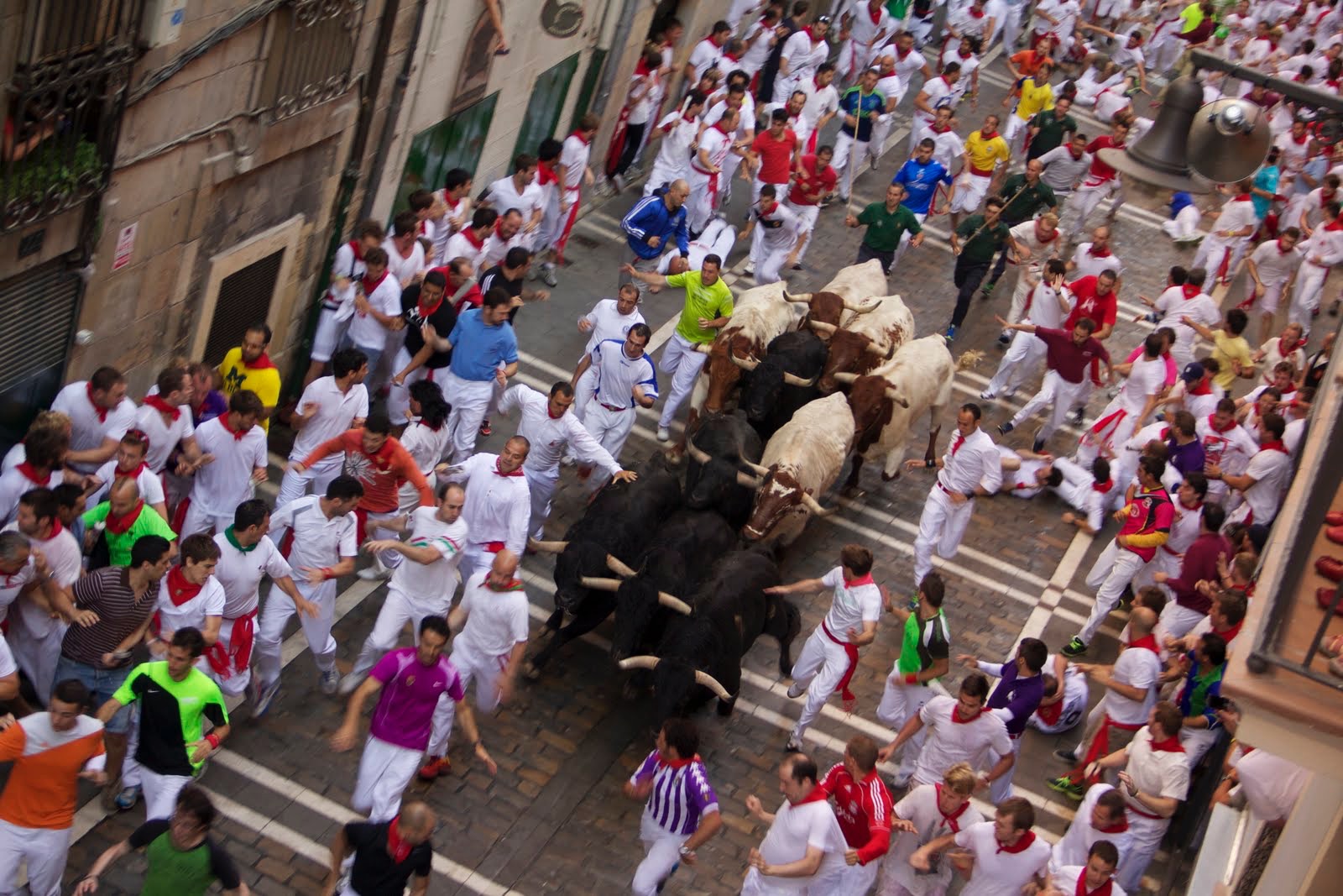 Runners sprinting ahead of bulls along Estafeta Street during the Running of the Bulls in Pamplona, Spain